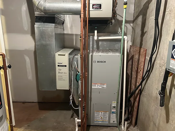 Bosch air handler installed in a basement mechanical room with copper line sets and a media filter cabinet