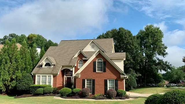 A two-storey brick and siding family home behind mature trees, the kind of Wichita-area house where one thermostat downstairs runs both floors