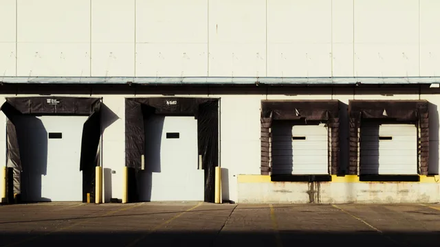 Four loading dock bays with roll-up doors and fabric dock seals along the side of a low commercial building