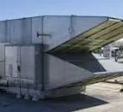 Make-up air unit outdoors, its sloped intake hood facing out from the side of the cabinet