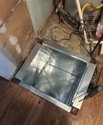 New sheet-metal return-air plenum fitted into a floor opening beside a furnace