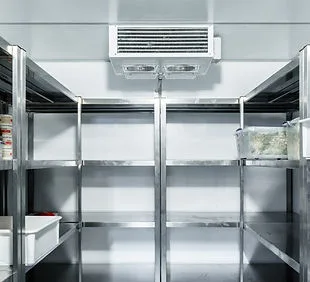 Interior of a walk-in cooler, with an evaporator unit mounted high on the back wall and stainless steel shelving down both sides